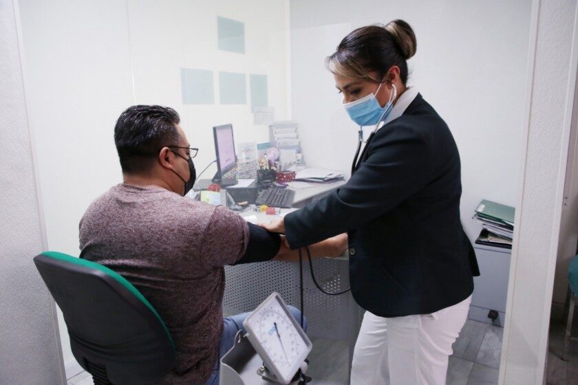 Enfermera del IMSS midiendo presión arterial