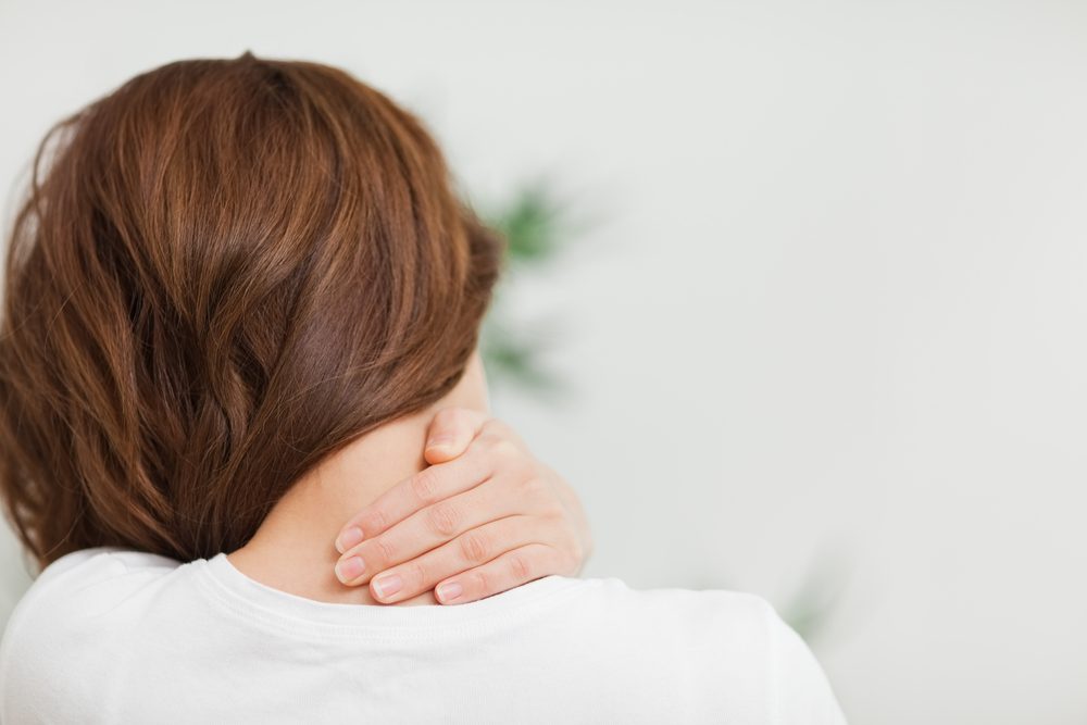 Primer plano de una mujer morena masajeando su cuello