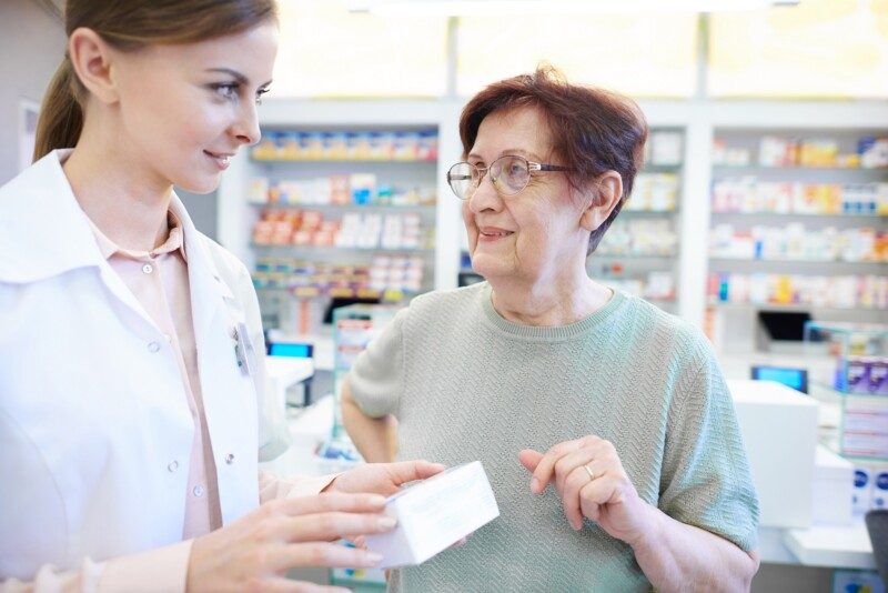 Enfermera asisteindo a ault mayor en farmacia