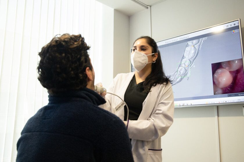 Odontologa revisando con equipo digital un paciente