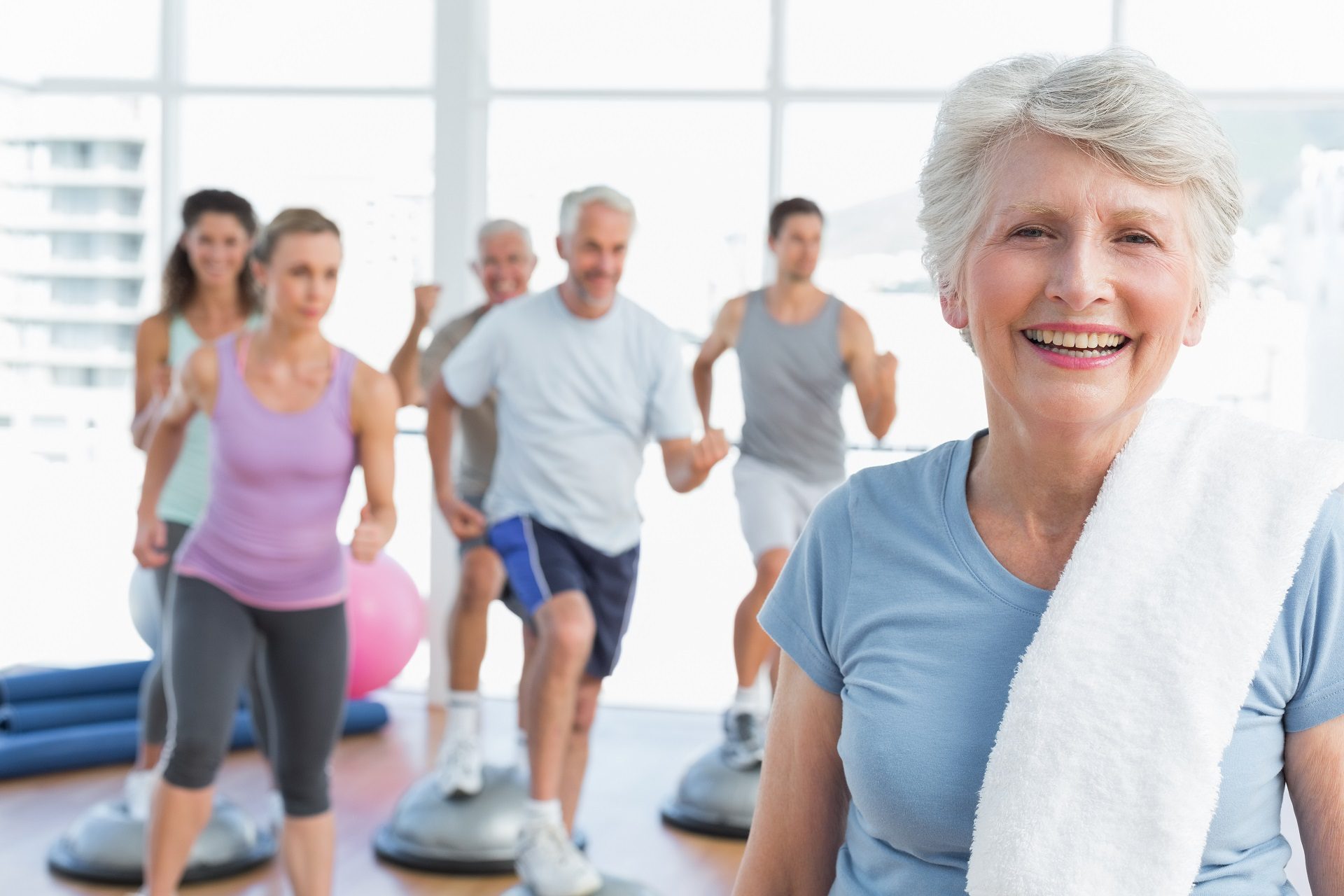 Adulta mayor con personas que hacen ejercicio en un gimnasio