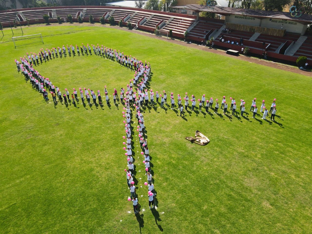 Personal del IMSS forma lazo rosa en cancha de futbol de la Unidad Deportiva Morelos, de la Alcaldía Gustavo A. Madero