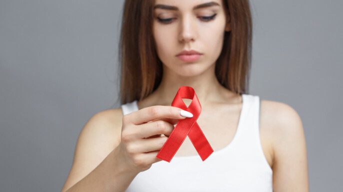 Mujer con cinta roja para concienciar sobre la enfermedad por el VIH