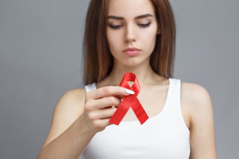 Mujer con cinta roja para concienciar sobre la enfermedad por el VIH