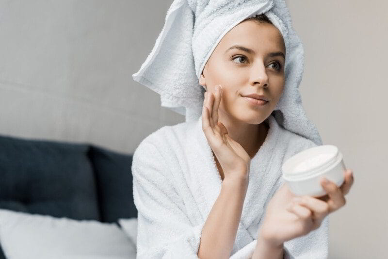 Joven aplicando crema en rostro