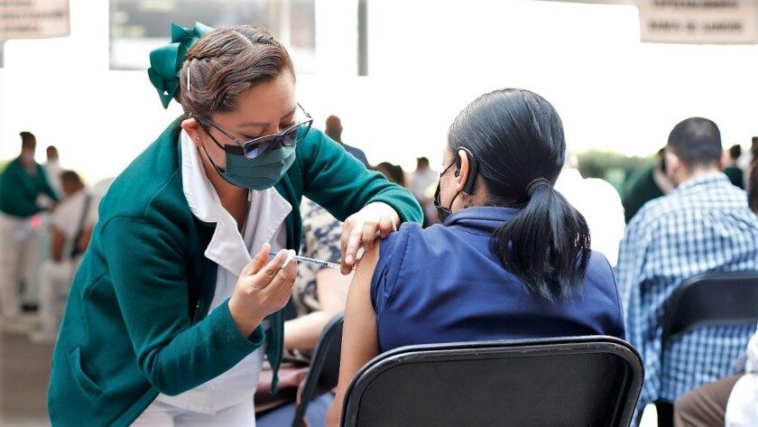 Enfermera aplicando vacuna a mujer sentada