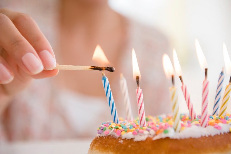 acercamiento a mano encendiendo vela en un pastel de cumpleaños