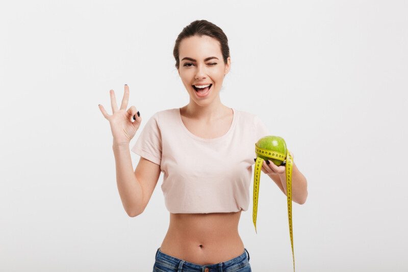 Mujer sosteniendo manzana atada con cinta métrica