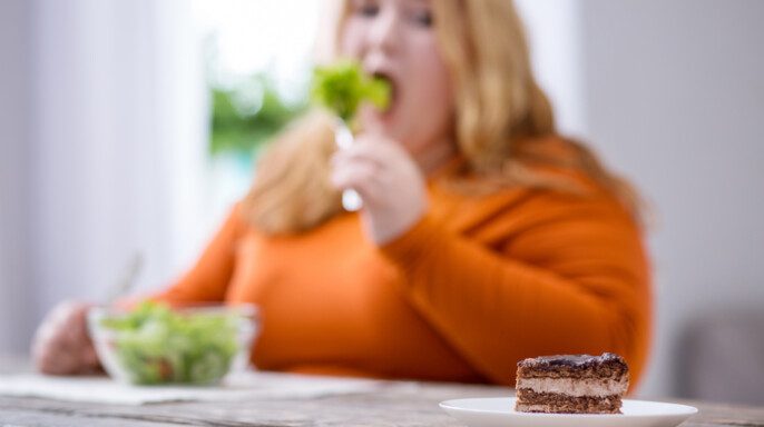 Mujer con obesidad desolada mirando galletas