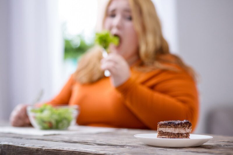 Mujer con obesidad desolada mirando galletas