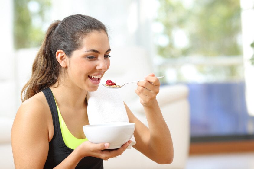 Deportiva comiendo cereales después del deporte en casa