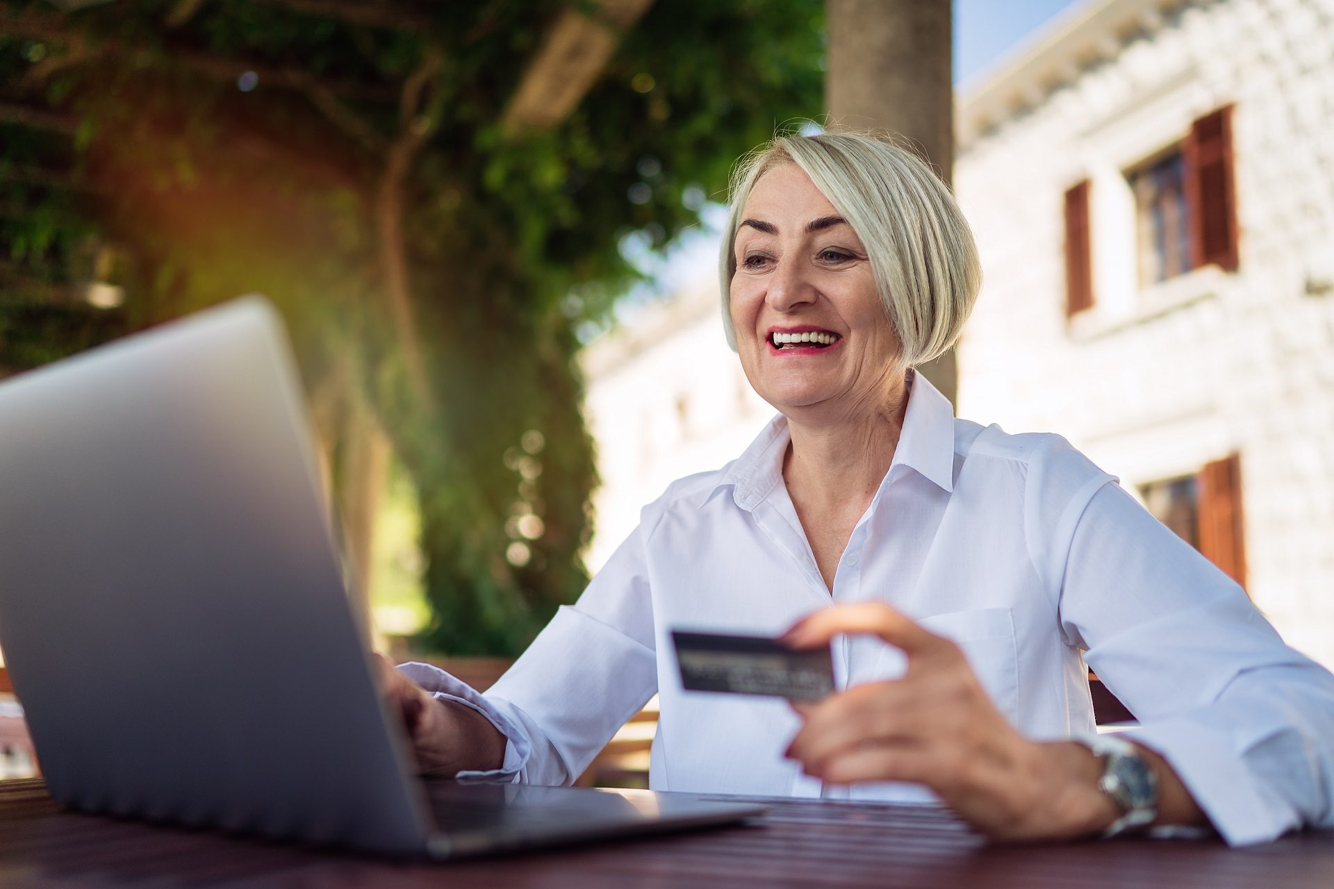 mujer adulta mayor usando computadora en un café