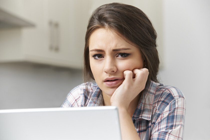 Adolescente chica víctima de acoso en línea con el ordenador