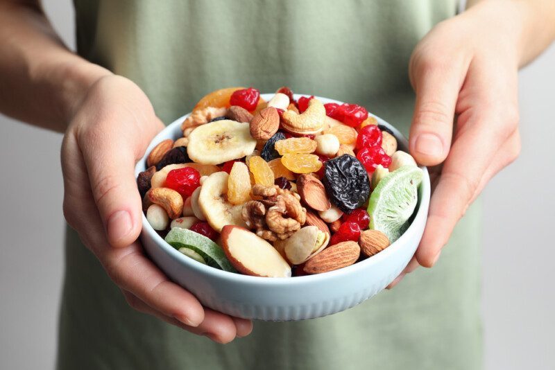 Mujer joven sosteniendo plato con diferentes frutos secos