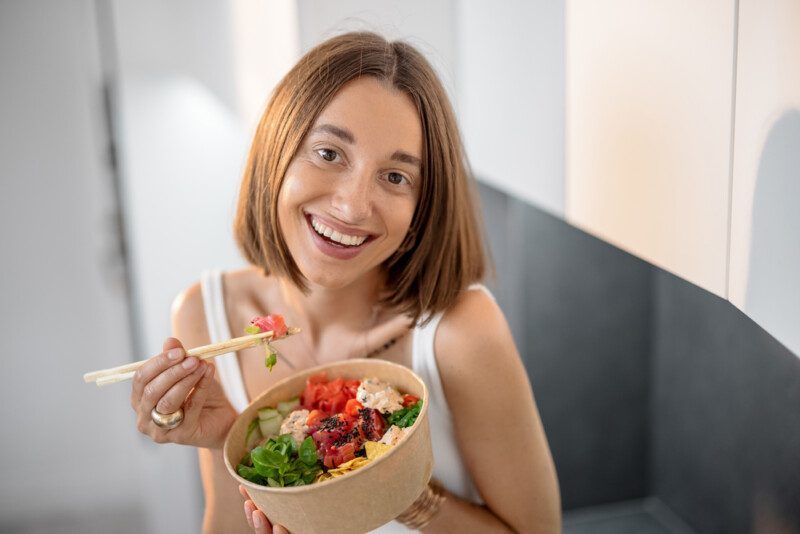 Retrato de una mujer feliz con un tazón saludable con atún