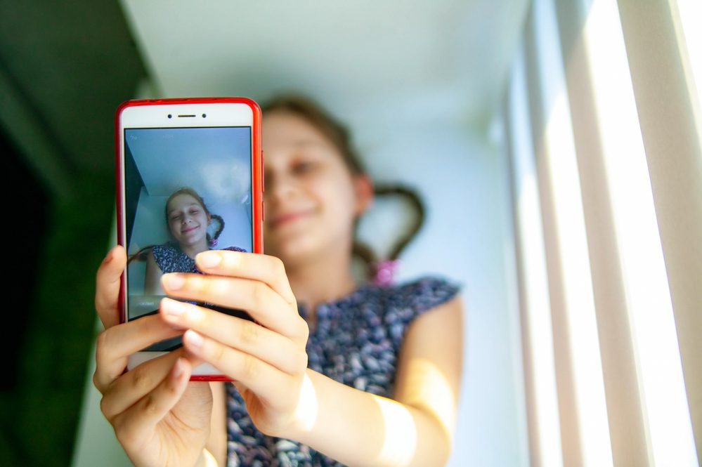 Niña sonriente tomando selfie en el teléfono