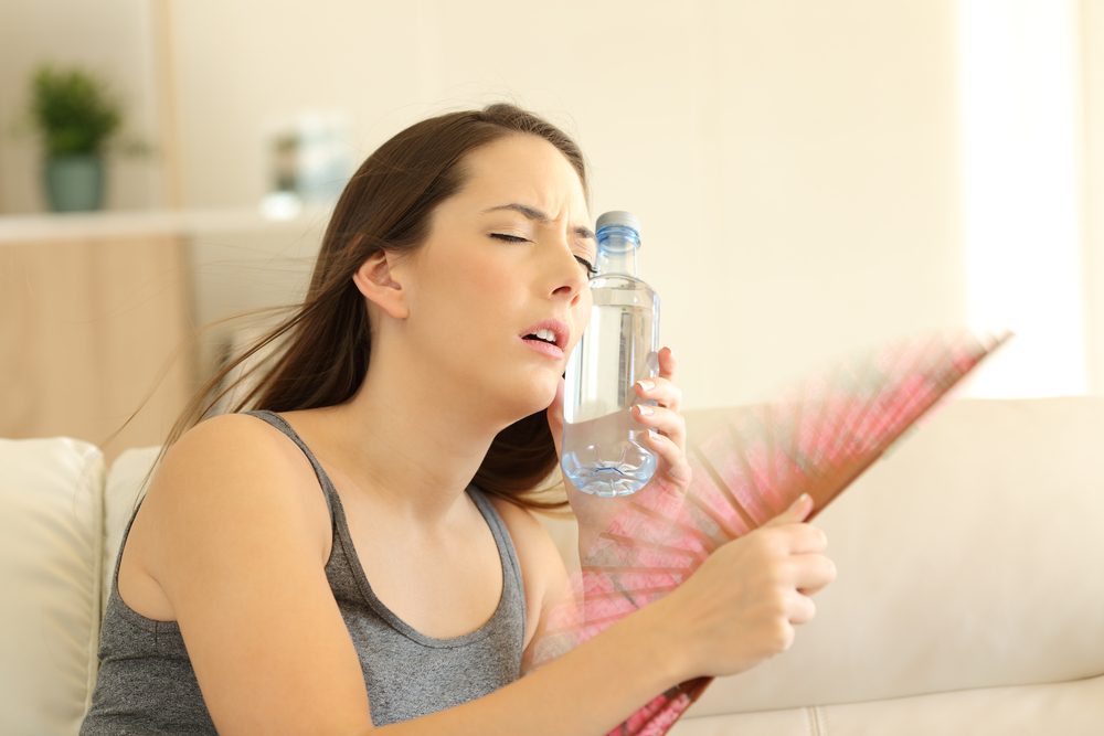 Chica sufriendo un golpe de calor refrescante con un ventilador