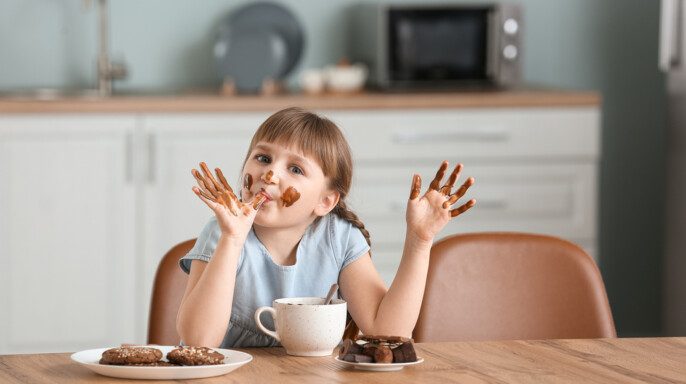 Linda niña comiendo chocolate en la cocina