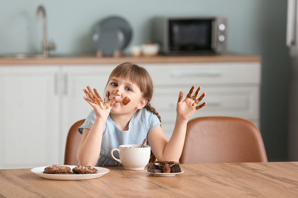 Linda niña comiendo chocolate en la cocina