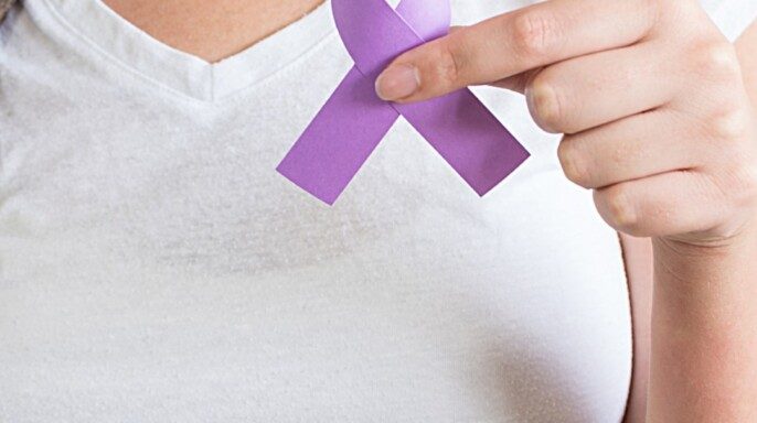 A woman holding a purple ribbon of the International Day for the Elimination of Violence Against Women