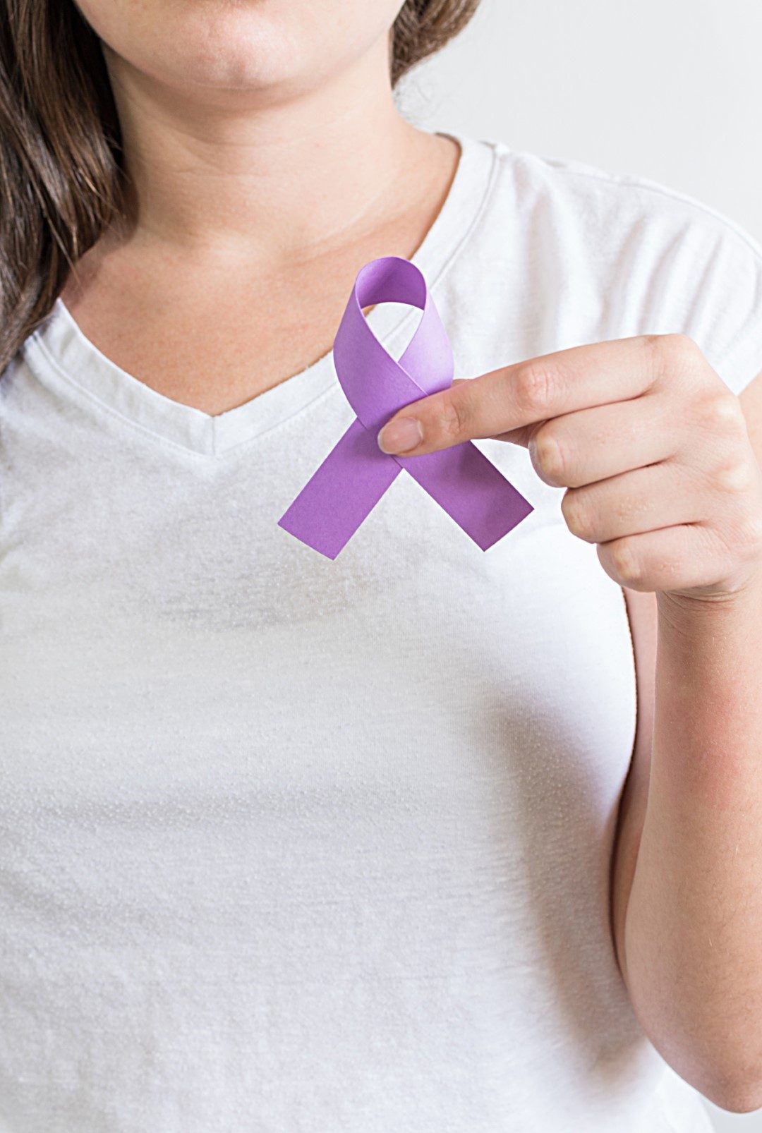 A woman holding a purple ribbon of the International Day for the Elimination of Violence Against Women