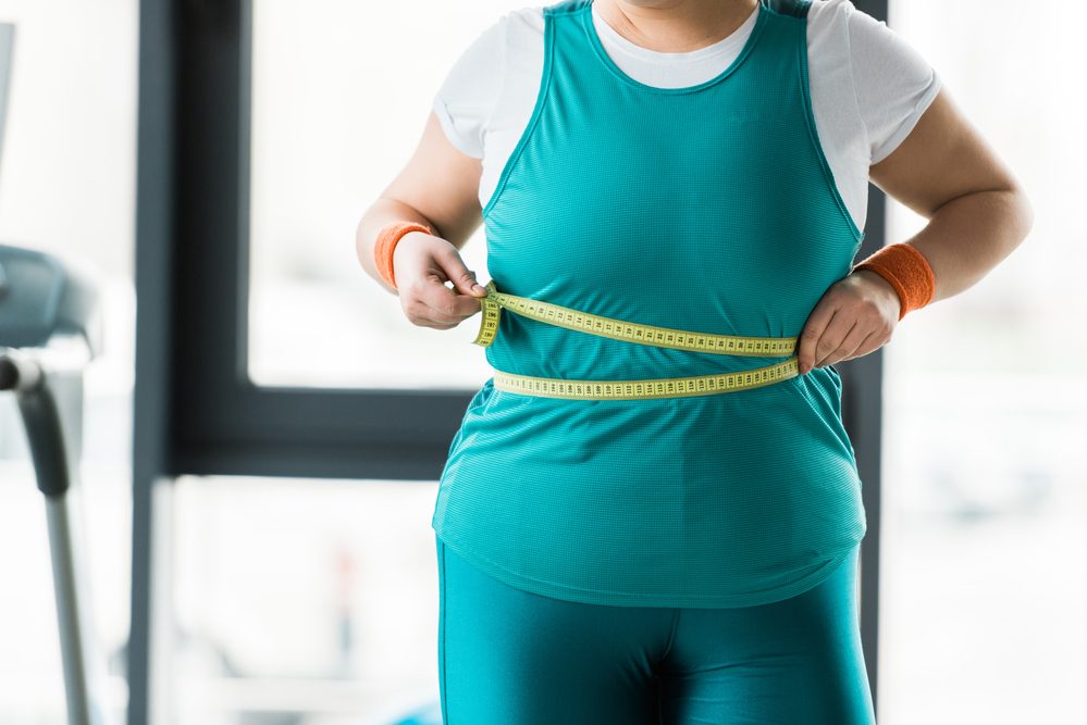 Vista Recortada Niña Con Sobrepeso Que Mide Cintura Gimnasio — Foto de Stock Vista recortada de la niña con sobrepeso que mide la cintura en el gimnasio.