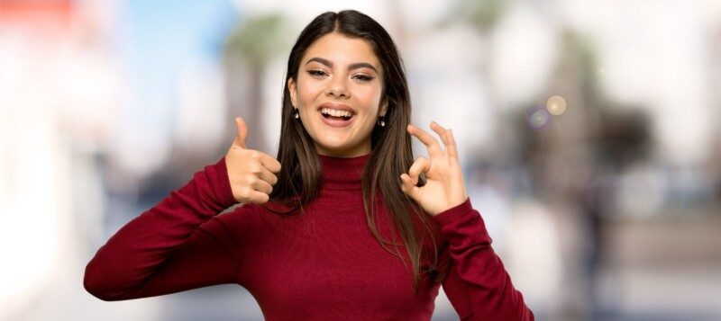 Mujer sonriendo y con señal de aprobación y OK