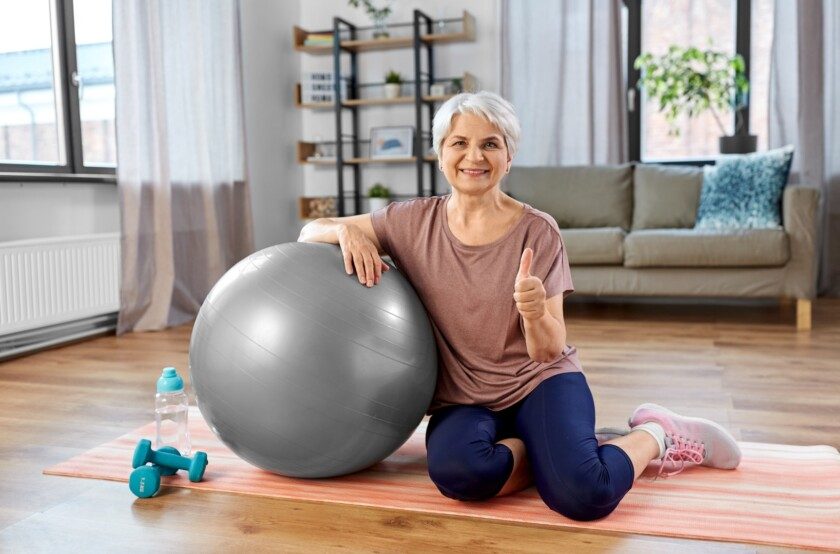adulta mujer mayor sonrie con bola de ejercicio en casa