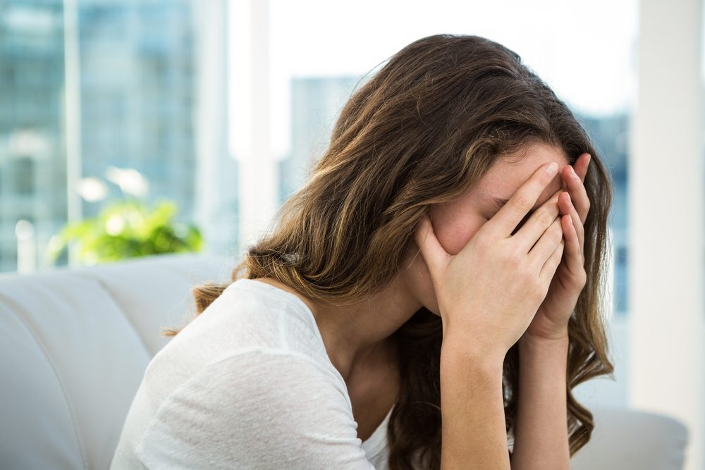 mujer triste sentada en el sofá.