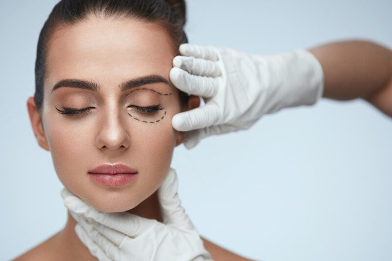 Primer plano de las manos esteticistas tocando la cara de paciente joven — Foto de Stock Primer plano de las manos esteticistas tocando la cara de paciente joven