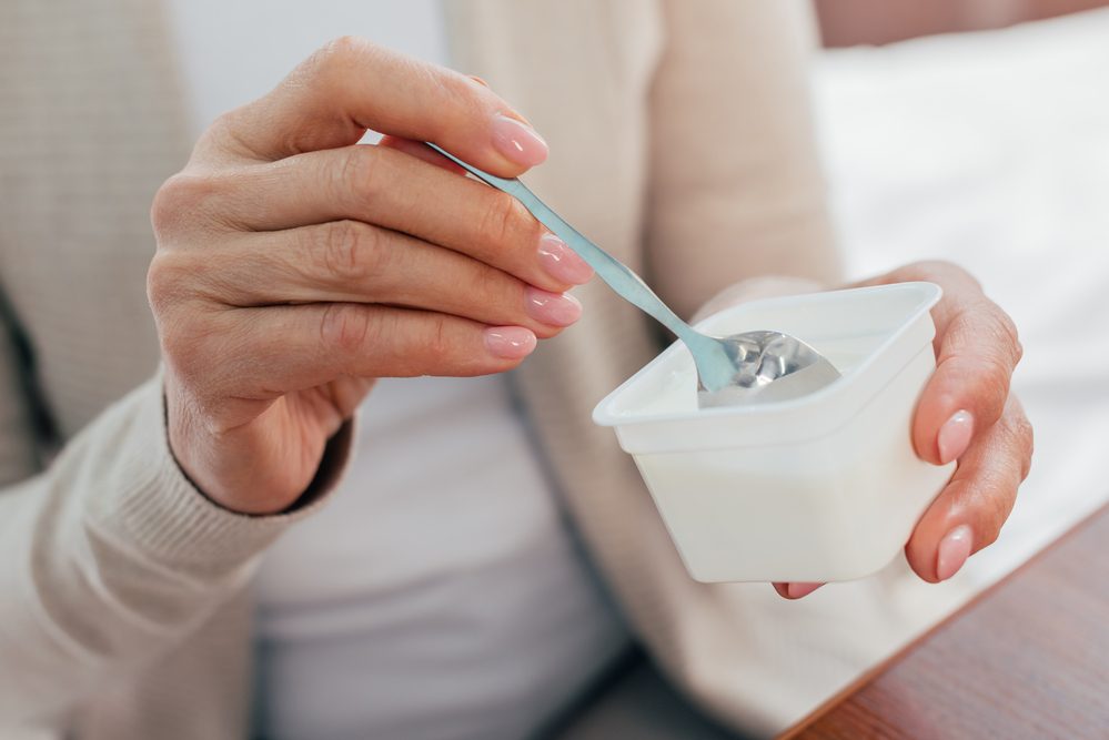 Mujer mayor comiendo yogur.