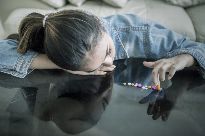 Adolescente femenina contando drogas en la mesa.