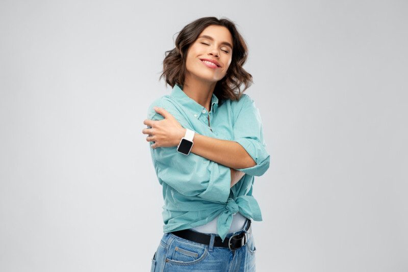 Sonriente mujer con reloj inteligente abrazándose