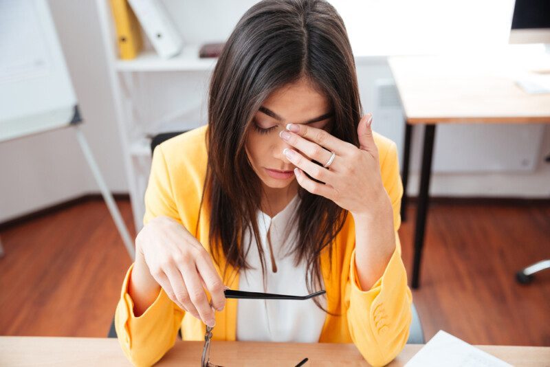 Mujer de negocios cansada sentada en su lugar de trabajo — Foto de Stock Mujer de negocios cansada sentada en su lugar de trabajo