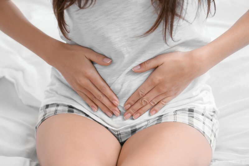 Mujer joven sufriendo de dolor abdominal.