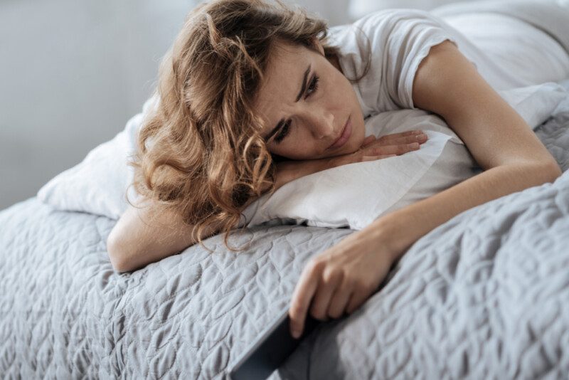 Mujer deprimida triste sosteniendo su teléfono celular — Foto de Stock Señora confundida pensando en su problema.