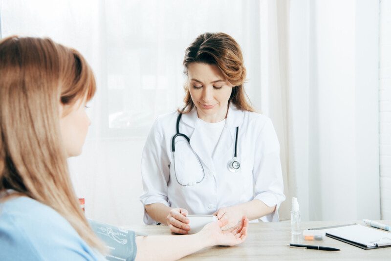 Vista recortada del paciente y el médico que mide la presión arterial