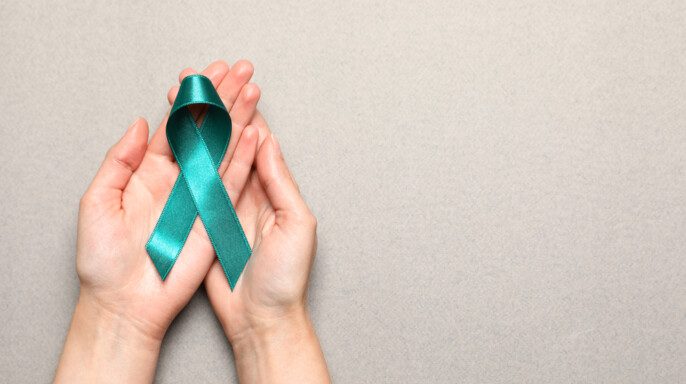 Mujer sosteniendo cinta de conciencia verde azulado sobre cáncer cervicouterino