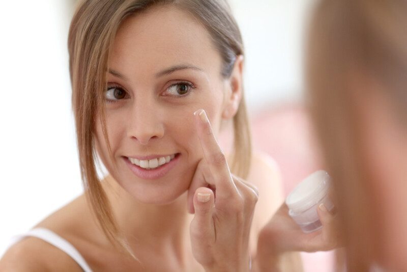 Chica poniendo crema anti-envejecimiento en su cara — Foto de Stock Chica poniendo crema anti-envejecimiento en su cara.