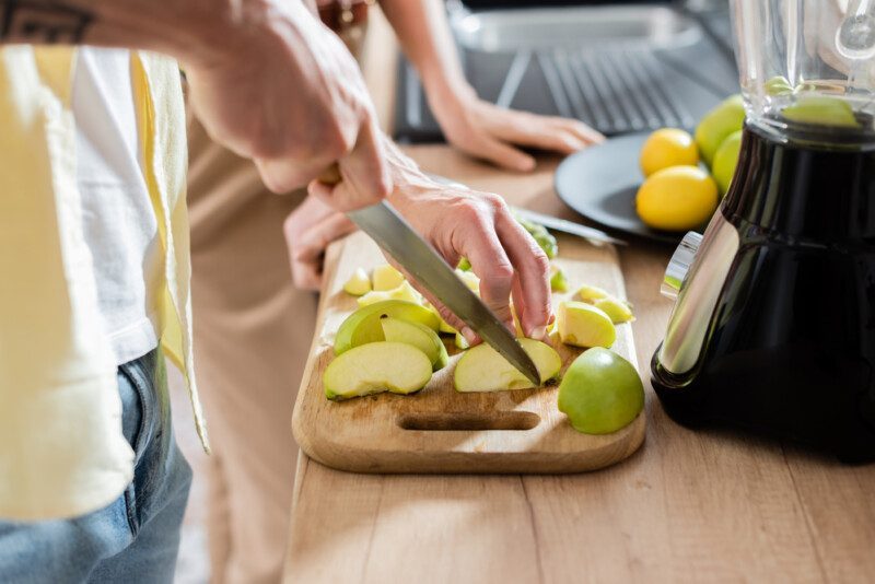 Cortando manzana cerca de licuadora.