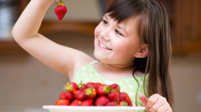 Feliz niña está comiendo fresas — Foto de Stock New Borrar fondo Guardar Compartir Muestra Feliz niña está comiendo fresas