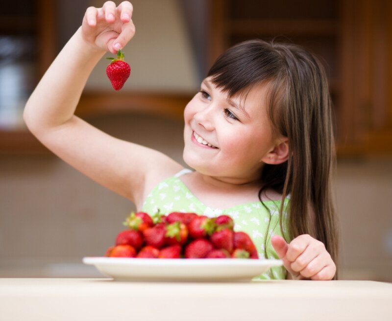 Feliz niña está comiendo fresas — Foto de Stock New Borrar fondo Guardar Compartir Muestra Feliz niña está comiendo fresas