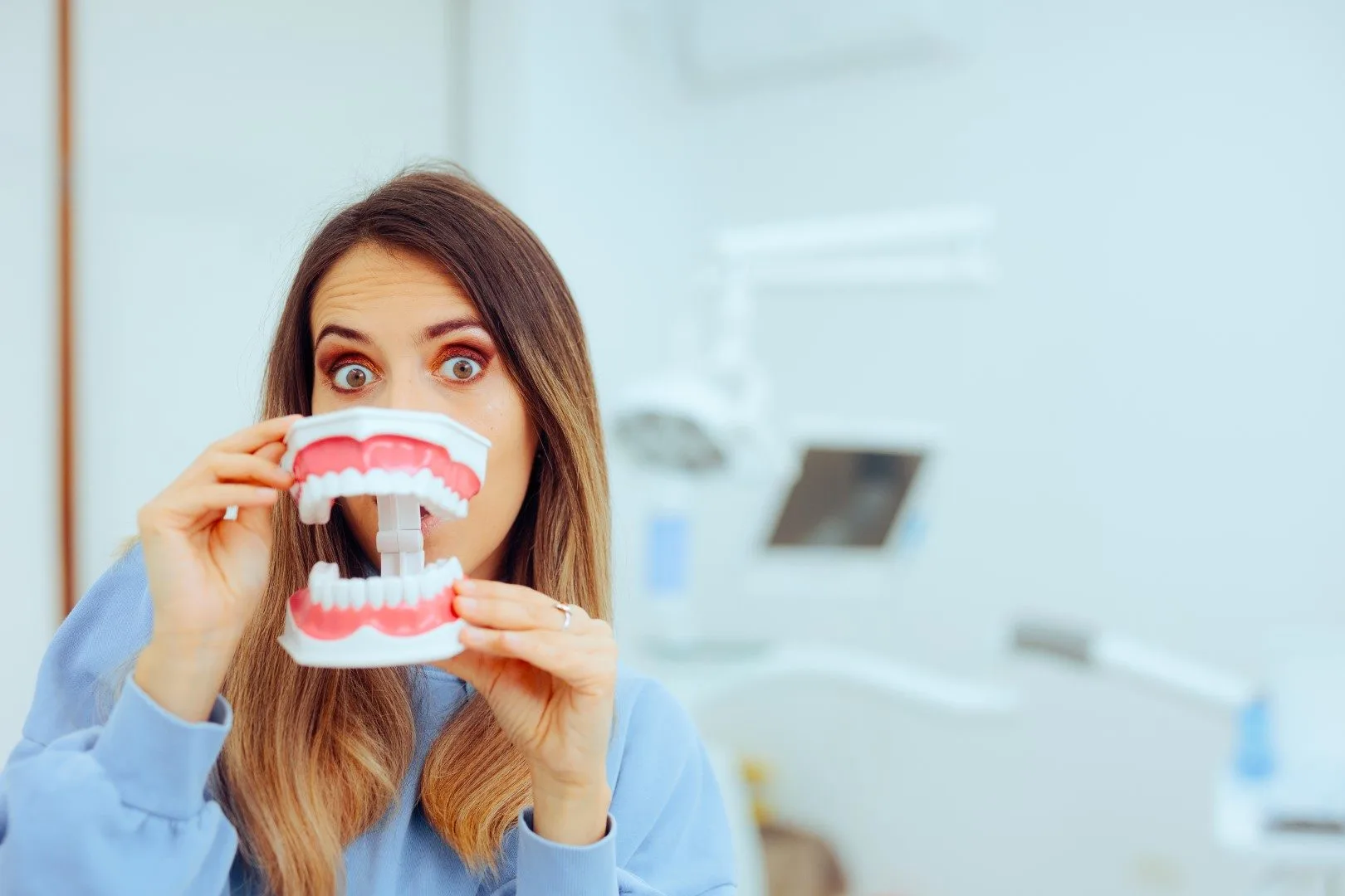 mujer divertida sosteniendo un modelo de dientes para informare de prevención del cáncer en boca