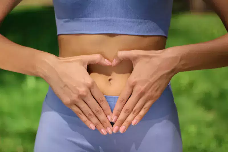 Mujer haciendo signo de corazón para prevenir las enfermedades digestivas