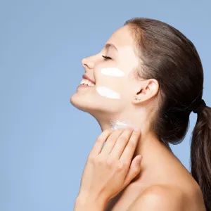 Portrait of a beautiful young brunette woman using skin care product.