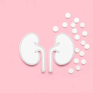 Paper kidneys with pills on pink background