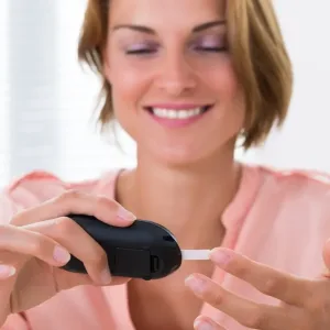 Close-up Of Young Happy Woman Checking Glucose Level With Glucometer